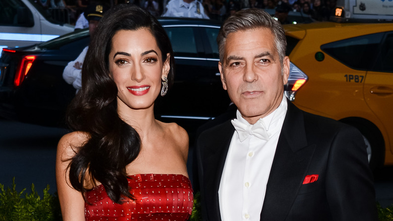 Amal Clooney and George Clooney posing at event
