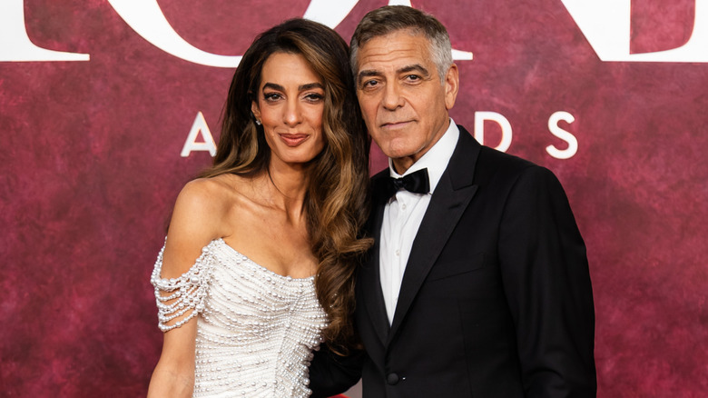 Amal Clooney and George Clooney posing at event