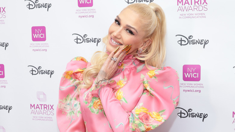 Gwen Stefani posing in pink puffy sleeve floral dress with hand on face