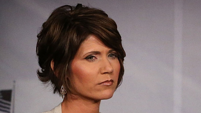 Kristi Noem sitting down while wearing an orange dress.