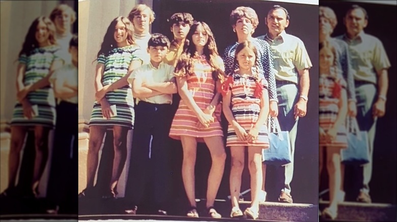 Christopher Ciccone with his arms crossed standing next to Madonna in their family photo
