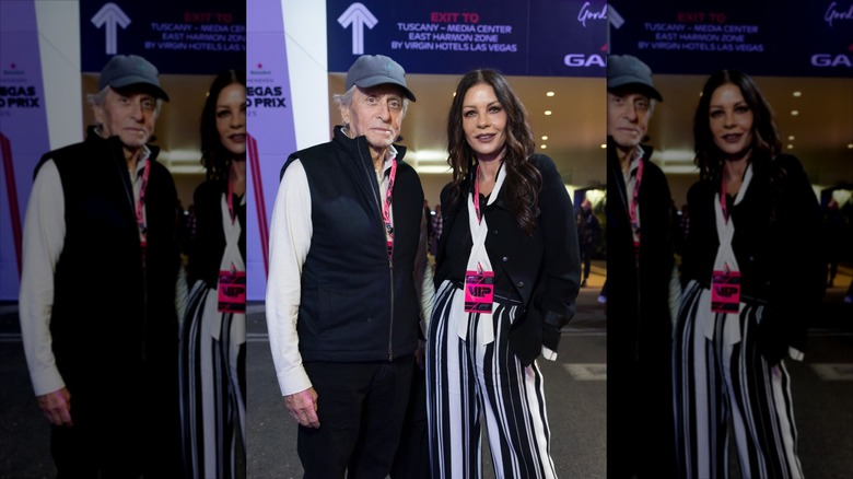 In an airport, Michael Douglas in a baseball cap with Catherine Zeta-Jones.