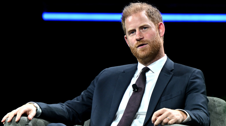 Prince Harry sitting in a chair wearing a suit and tie
