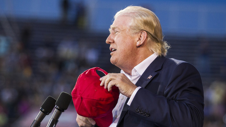 Republican presidential candidate Donald Trump removes his hat to show that his hair is real during a political rally at Ladd-Peebles Stadium on August 21, 2015 in Mobile, Alabama (2015)