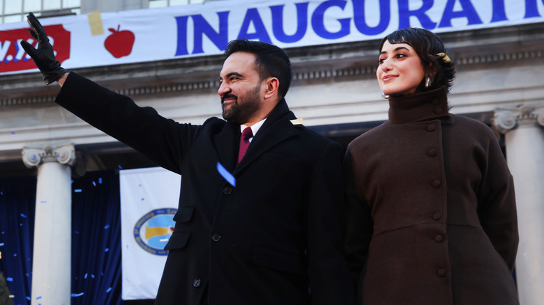 Zohran Mamdani and Rama Duwaji waving to a crowd at the inauguration.