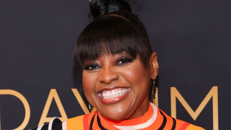 Sherri Shepherd speaking into a microphone, wearing a gold dress