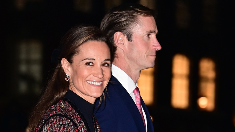 Closeup of Pippa Middleton smiling at camera as James Matthews walks beside her