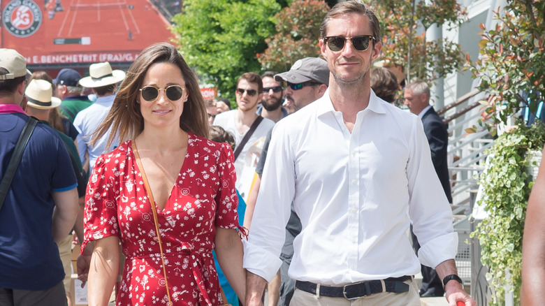 Pippa Middleton and James Matthews holding hands while walking in sunglasses