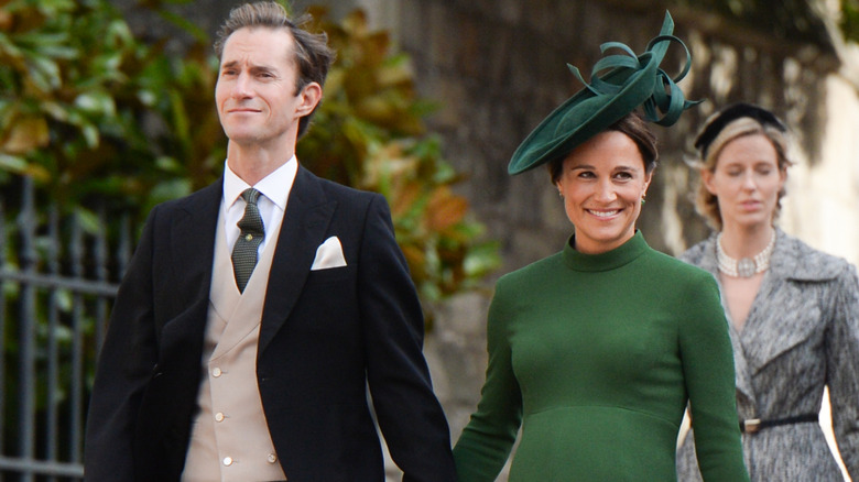 A smiling Pippa Middleton and James Matthews walking hand in hand
