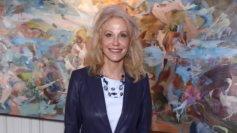 Kellyanne Conway smiling at an event in black leather jacket with a white shirt underneath