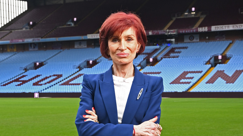 Sharon Osbourne standing on a stadium field in a navy blazer