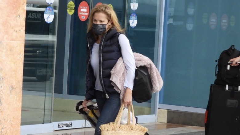 Heidi Cruz wearing face mask and dragging luggage at the airport
