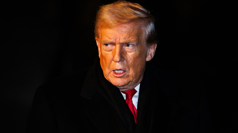 Donald Trump looking outraged and orange in a black suit with a white shirt and a red tie
