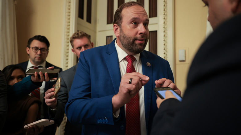 Jason Smith speaking to reporters while gesturing with his hands in a blue suit