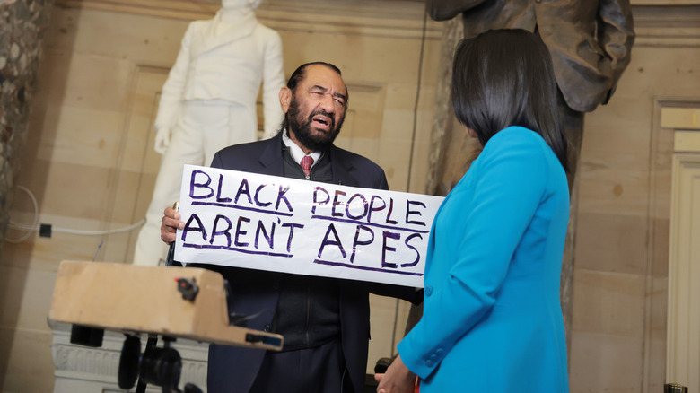 Rep. Al Green holding up a sign that reads "Black People Aren't Apes" at the 2026 SOTU