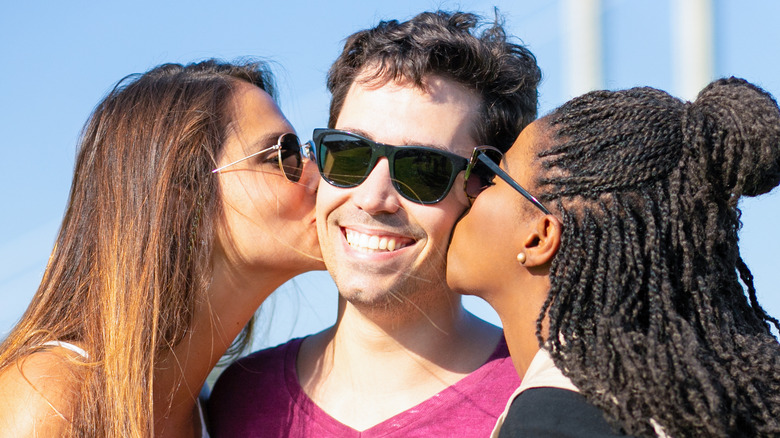 Two women kissing a man