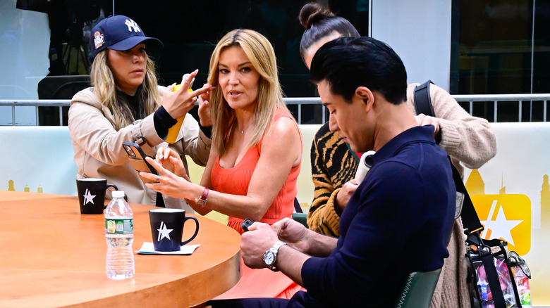 Kit Hoover and Mario Lopez checking their phones while in hair and makeup ahead of filming for Access Hollywood