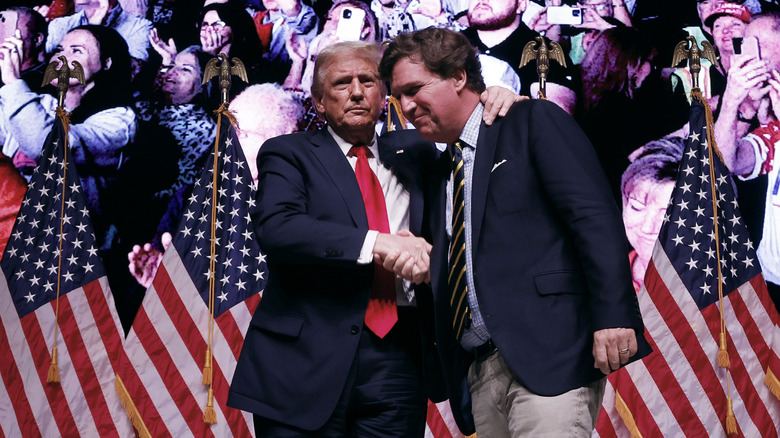 Donald Trump shakes hands with Tucker Carlson at the conclusion of a conversation during Carlson's Live Tour at the Desert Diamond Arena on October 31, 2024 in Phoenix, Arizona.