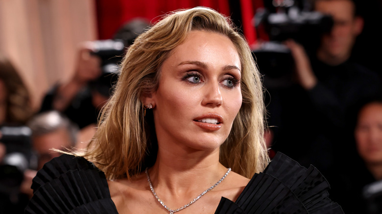 Miley Cyrus posing in a black dress