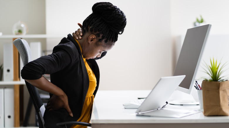 Woman having neck and back pain while working on the computer