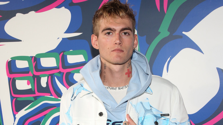 Presley Gerber posing on the red carpet in a patterned whit jacket and light-blue hoodie