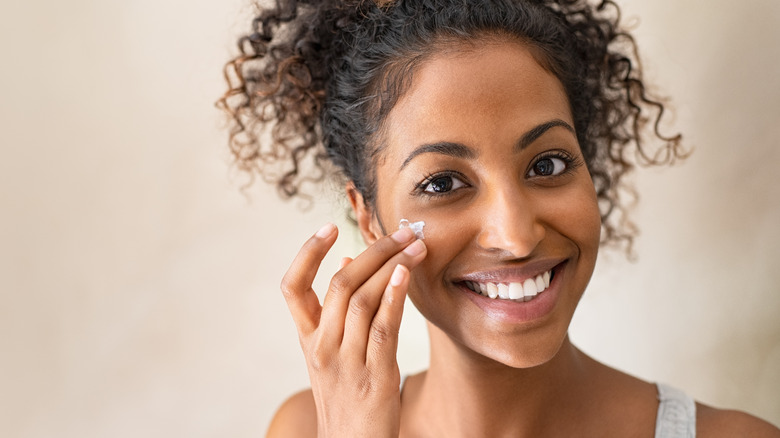 woman applying moisturizer on face