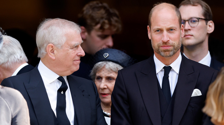 Prince Andrew looking at Prince William while both are wearing suits