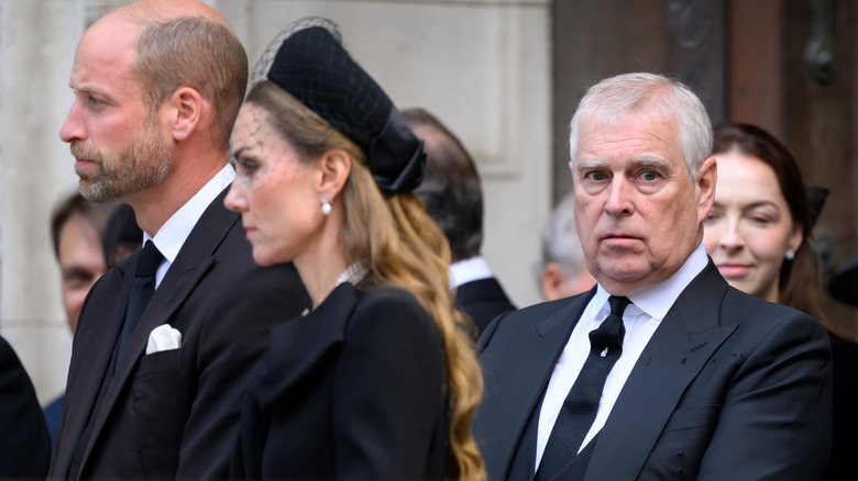 Prince Andrew standing behind Prince William and Princess Catherine