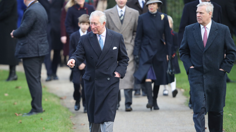 Prince Andrew and King Charles III walking in front of royal family