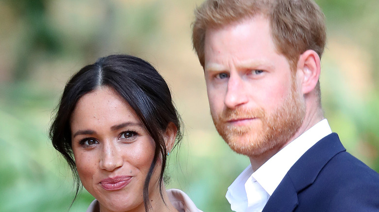 Meghan Markle with slight smile and Prince Harry looking concerned