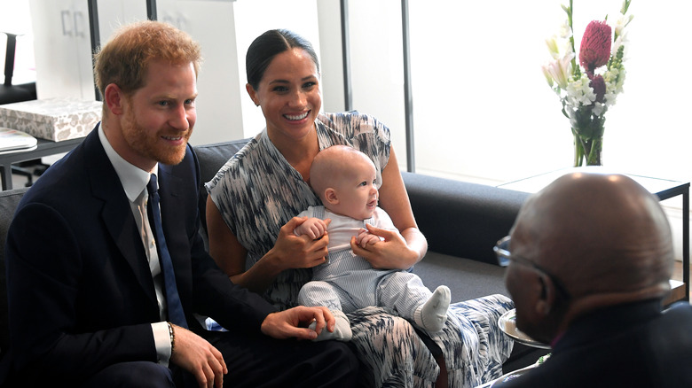 Prince Harry, Duke of Sussex, sitting next to Meghan Markle, Duchess of Sussex, who's holding Prince Archie