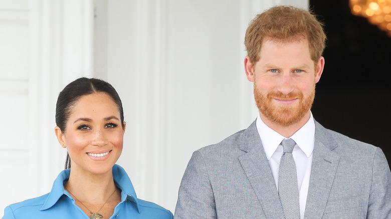 Meghan Markle and Prince Harry smiling as they pose for a photo