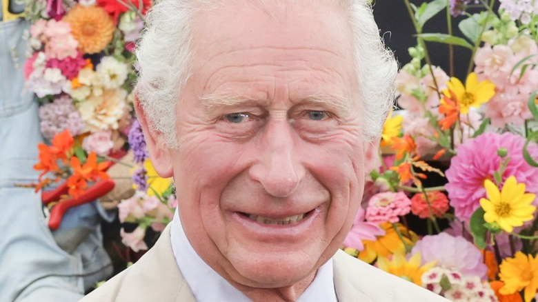 Prince Charles smiling in front of flowers