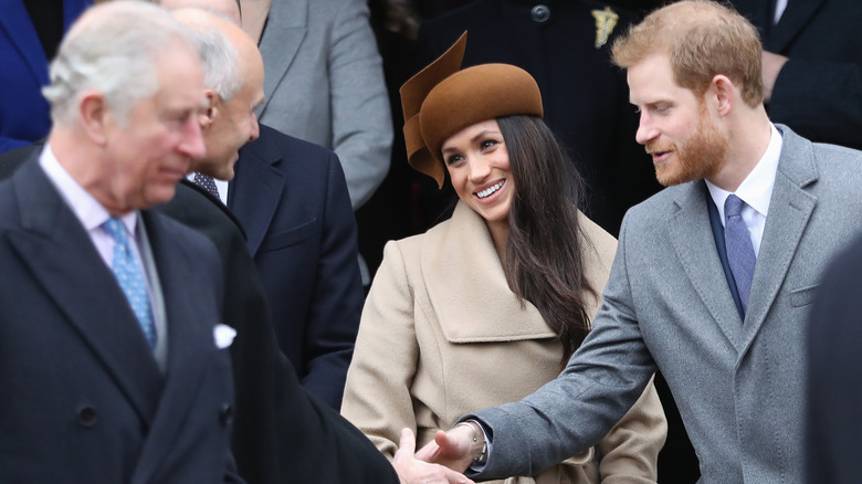 Prince Charles, Prince Harry, and Meghan Markle smiling 