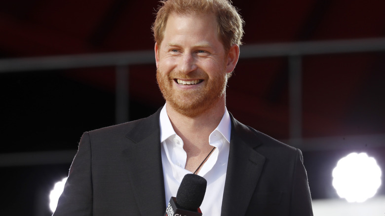 Prince Harry smiling onstage with a microphone