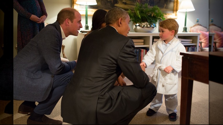 Prince William, First Lady Michelle Obama, and President Barack Obama squatting while talking with Prince George at Kensington Palace on April 22, 2016 in London, England (2016)