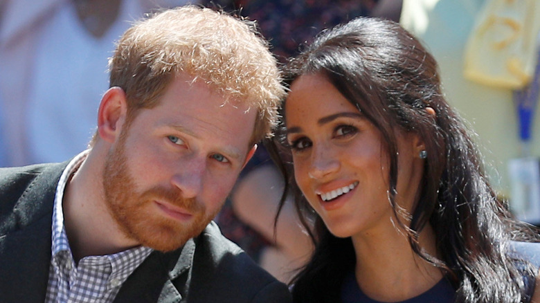 Prince Harry leaning in close to listen to Meghan Markle