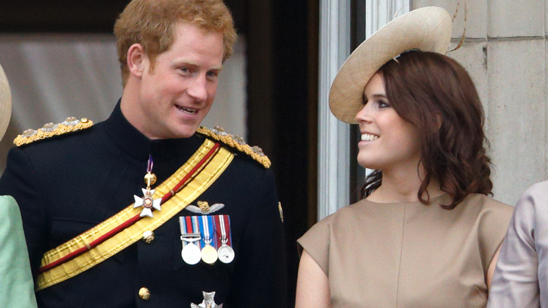 Prince Harry speaking to Princess Eugenie as she listens and smiles