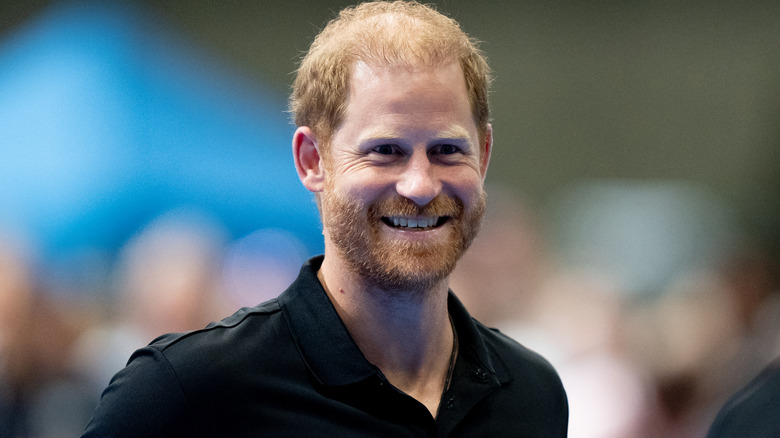 Prince Harry smiling widely in a black shirt