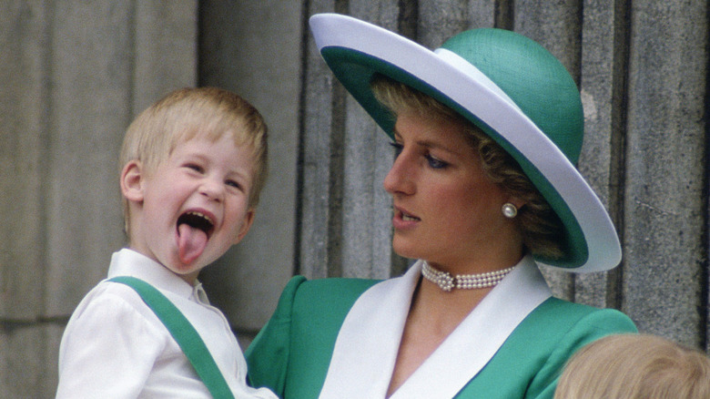 Princess Diana holding young Prince Harry while he sticks his tongue out
