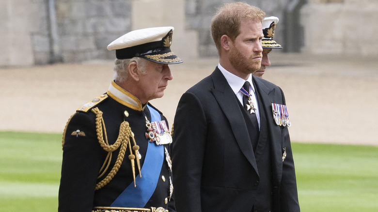 King Charles III and Prince Harry walking side by side.