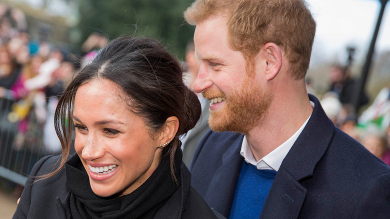 Meghan and Harry smiling while meeting fans