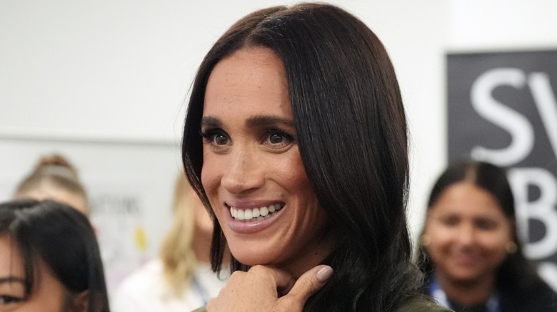 Meghan Markle smiling with her hand under her chin
