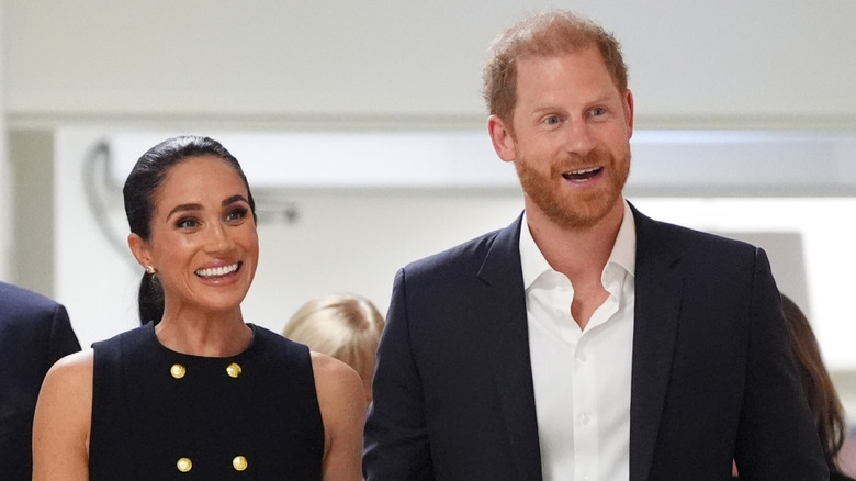 Meghan Markle and Prince Harry smiling and looking to the side