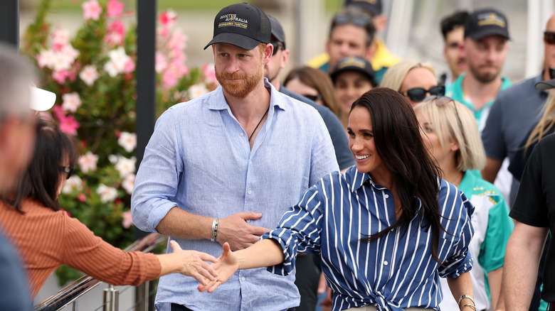 Prince Harry and Meghan Markle greeting fans in a crowd