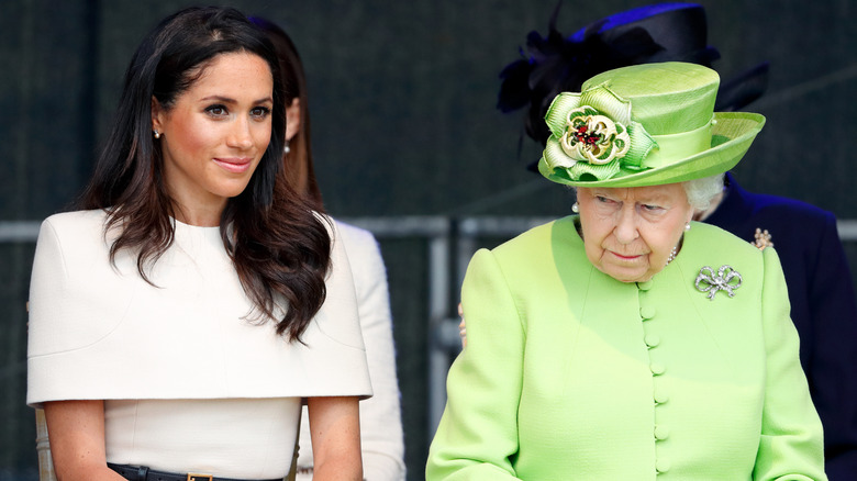 Queen Elizabeth II sitting beside Meghan Markle looking grumpy