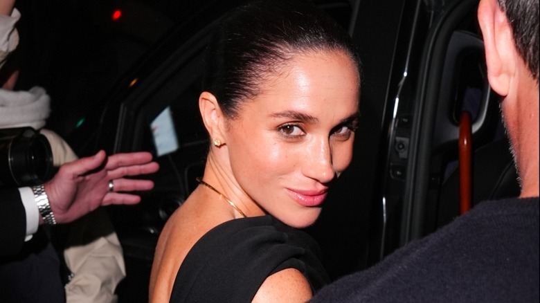 Meghan Markle looking over her shoulder at the cameras before stepping into a car