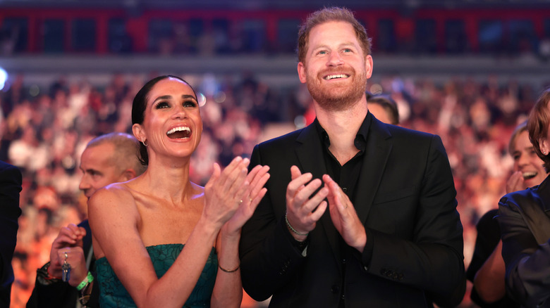 Meghan Markle and Prince Harry clapping and smiling at an event