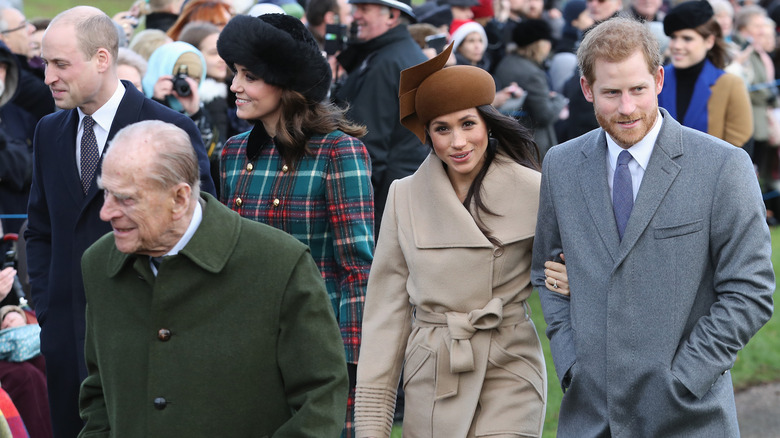 Prince Harry and Meghan Markle walk behind Prince Philip