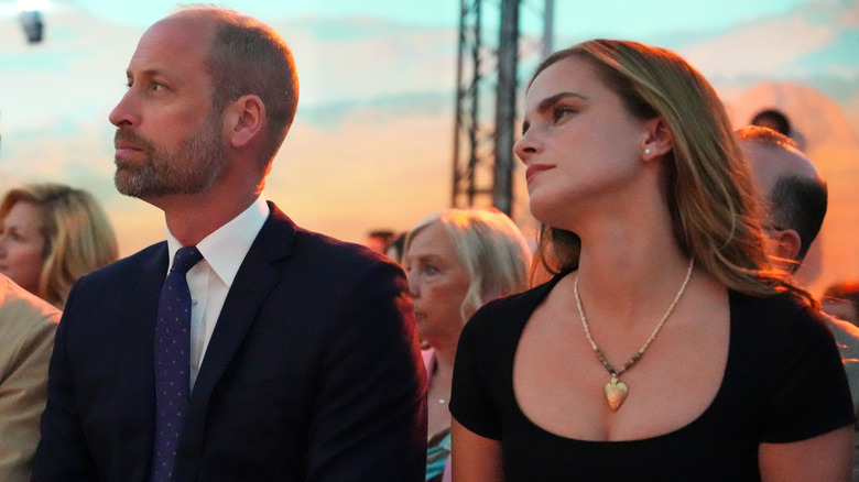 Prince William and Emma Watson sitting next to each other outdoors and watching an event.
